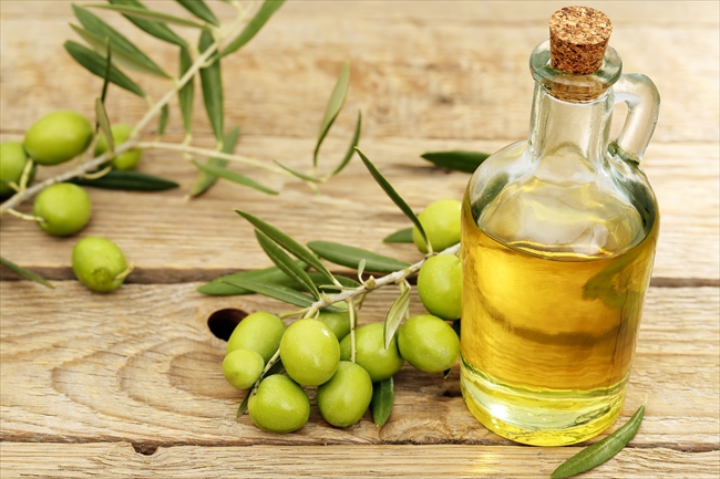 olive oil with branch of olive tree placed on wooden background
