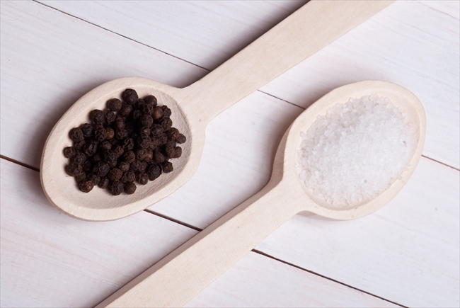 Spices. Rock salt and black pepper on a wooden spoons.